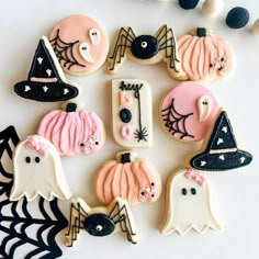 decorated halloween cookies arranged in the shape of ghostes and pumpkins on a white surface