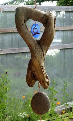 a piece of driftwood hanging from a chain with a blue glass heart on it