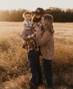 a woman holding a baby while standing in a field