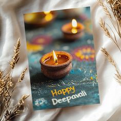 a happy deepavai greeting card sitting on top of some dried grass and candles