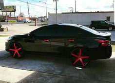 a black car with red spokes parked in front of a gas station