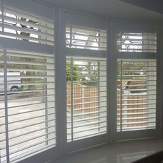 an empty room with three windows that have white shutters on the outside and inside