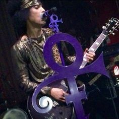 a man holding a guitar while standing in front of a purple ampel with an amp