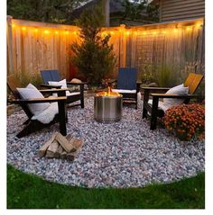 a fire pit surrounded by lawn chairs and lights in a backyard with gravel around it