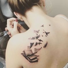 a woman with a book and birds tattoo on her back shoulder, behind her ear