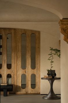 a living room with wooden doors and glass panels on the door, in front of a round table