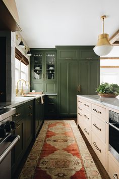 a kitchen with green cabinets and an area rug