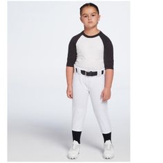 a young boy in white and black baseball uniform standing with his hands on his hips