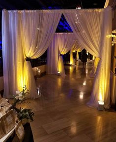 an indoor wedding venue decorated with white drapes and candles