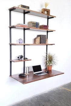 a laptop computer sitting on top of a wooden shelf next to a potted plant