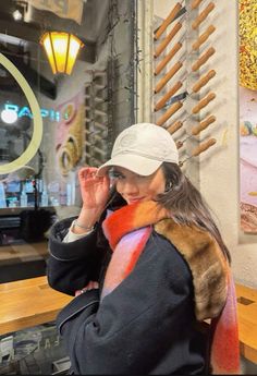 a woman wearing a hat and scarf sitting at a table