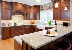 a large kitchen with wooden cabinets and marble counter tops, along with an island in the middle