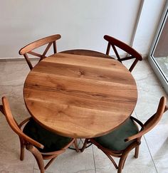 a wooden table with four chairs around it on the tile floor next to a window