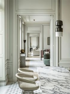 the hallway is lined with white walls and marble flooring, along with modern furniture