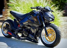 a black and gold motorcycle parked on the side of a road next to tall grass