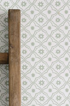 a wooden handle on a wall next to a white and green patterned wallcover