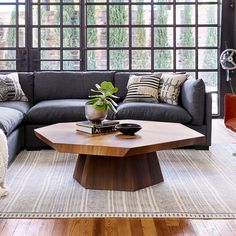 a living room with a couch, coffee table and large windows in it's walls