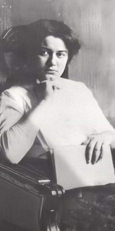 an old photo of a woman sitting at a table with a piece of paper in her hand