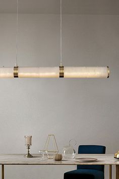 a dining room table with chairs and a light fixture hanging from it's ceiling