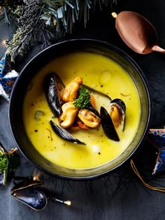 a bowl filled with mussels and sauce on top of a table next to christmas decorations