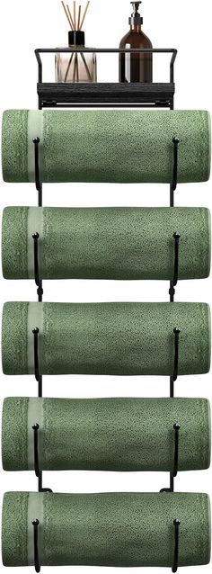 the towel rack has five green towels hanging from it's sides and two bottles on top