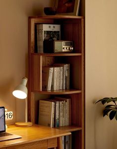 a laptop computer sitting on top of a wooden desk next to a bookshelf