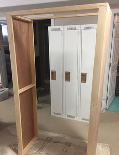 an unfinished room with two lockers in the middle and one door open to reveal another room