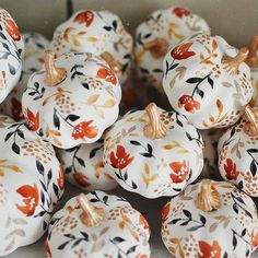 many white pumpkins with leaves and flowers painted on them are sitting in a box