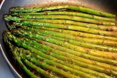 asparagus being cooked in a frying pan on the stove with seasonings