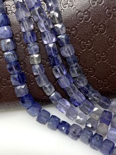 three strands of blue glass beads are next to a brown leather purse on a white surface