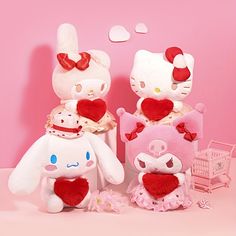 two hello kitty stuffed animals are posed next to each other in front of a pink background