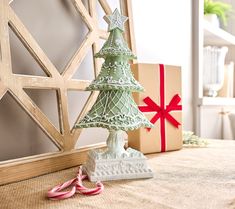 a small christmas tree sitting on top of a table next to a pair of pink scissors