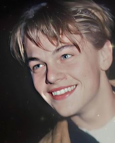 a close up of a person wearing a jacket and smiling at the camera with light shining on his face