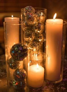 some candles are sitting next to each other on a table in front of a mirror ball