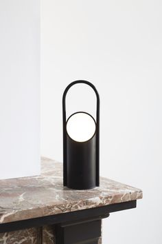 a black lamp sitting on top of a table next to a white wall and floor