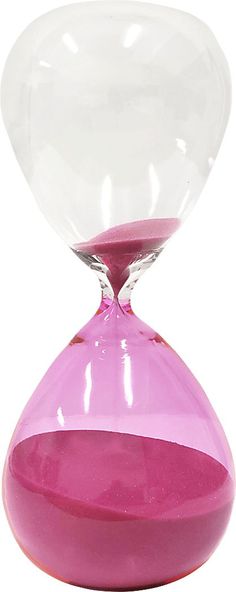 an hourglass sitting on top of a white table next to a pink vase with red liquid in it