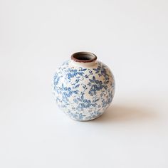 a blue and white flowered vase sitting on top of a white tablecloth covered floor