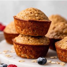 muffins stacked on top of each other with berries and oats around them