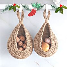 two hanging baskets filled with nuts and pine cones on top of a white countertop