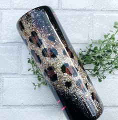 a black vase with gold and silver glitters on it next to a brick wall