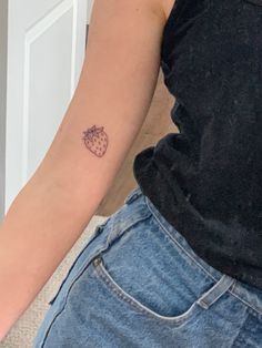 a person with a strawberry tattoo on their left arm and the other arm behind her