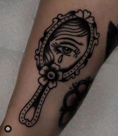 a close up of a person's arm with a tattoo on it and an eye looking in a mirror