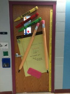 a bulletin board with pencils, ruler and eraser on it in front of a door