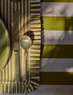 a table setting with silverware and green striped placemats on top of it