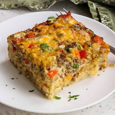 a white plate topped with a slice of casserole covered in cheese and vegetables