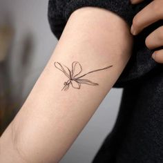 a woman's arm with a small flower tattoo on it