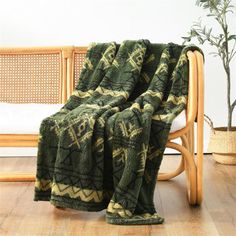 a green blanket sitting on top of a wooden chair next to a potted plant