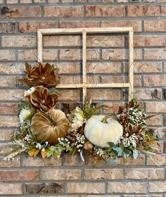 a brick wall with a window frame decorated with fall flowers and gourds on it