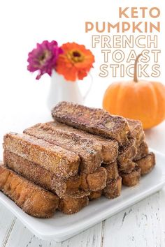 french toast sticks are stacked on a plate next to a vase with flowers and pumpkins