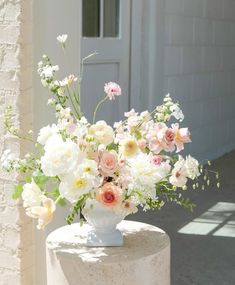 a vase filled with lots of flowers sitting on top of a white table next to a building